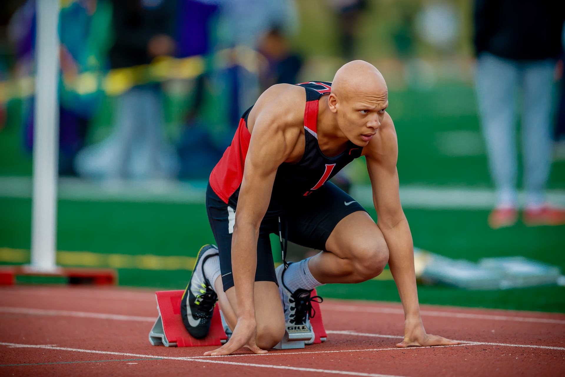 Sprinter coiled in starting blocks, peak-action, technically flawless.