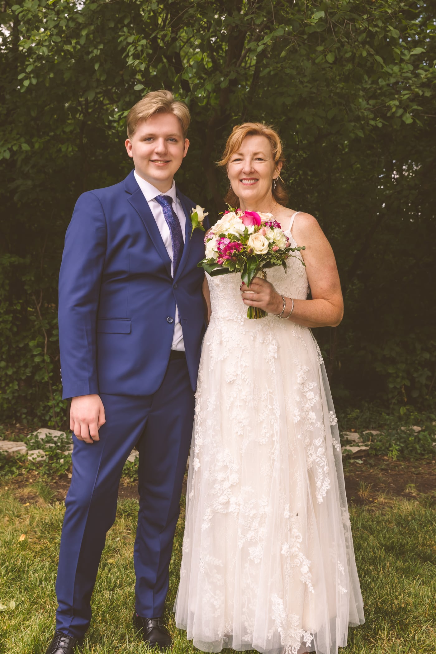 Couple outdoors, blue suit + bouquet.