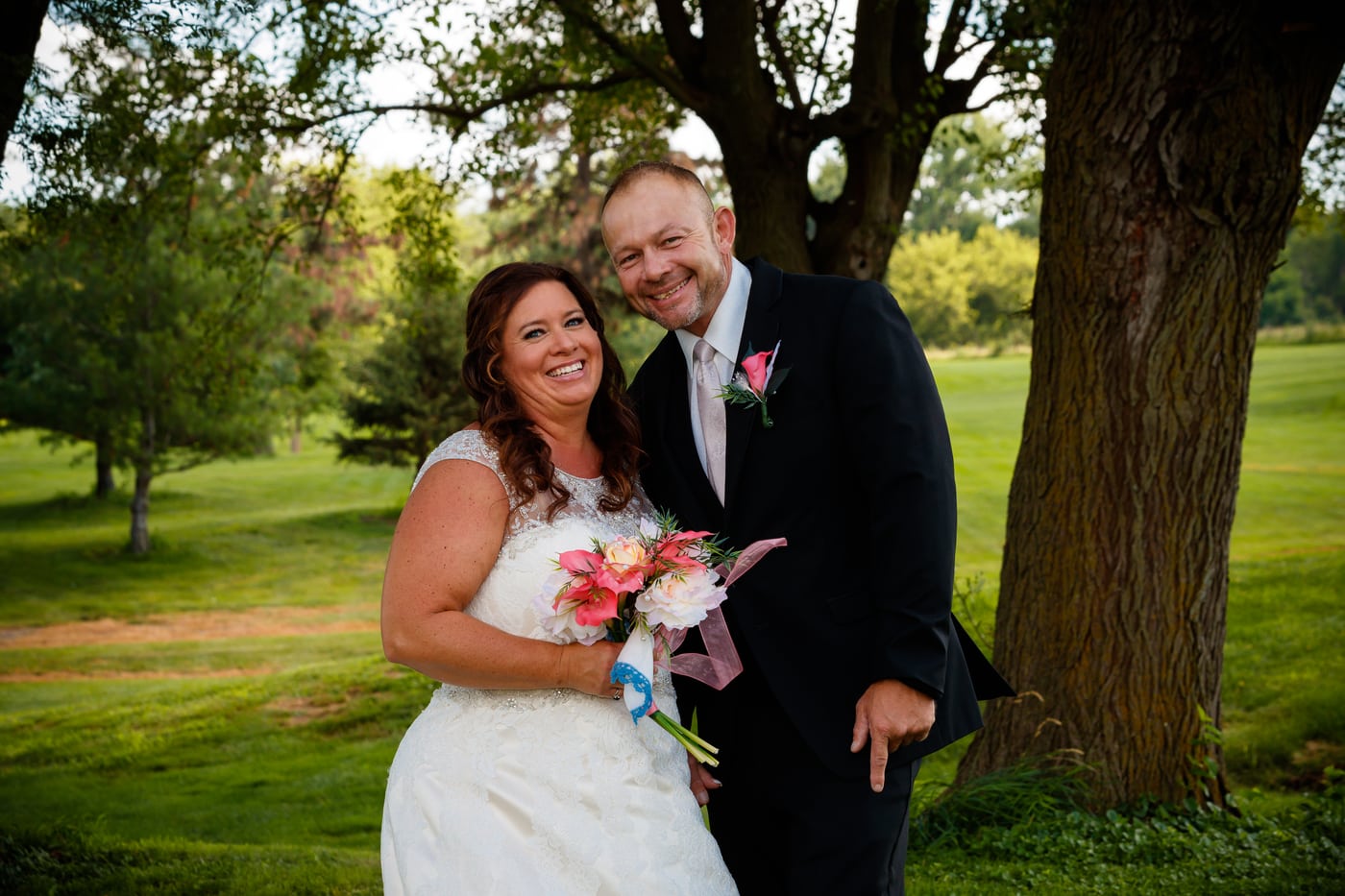 Wedding couple under trees, warm.
