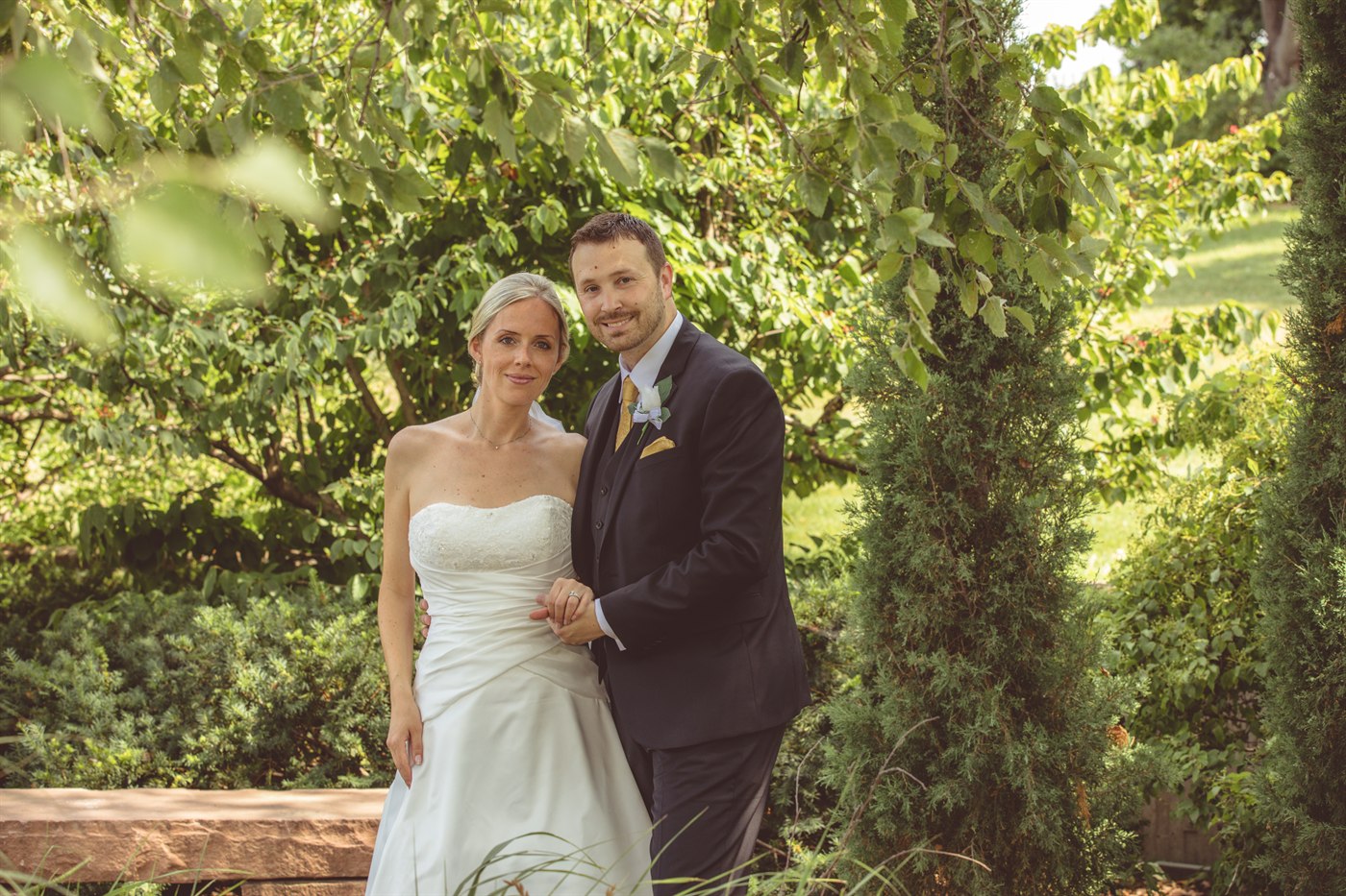 Outdoor wedding couple framed by trees.