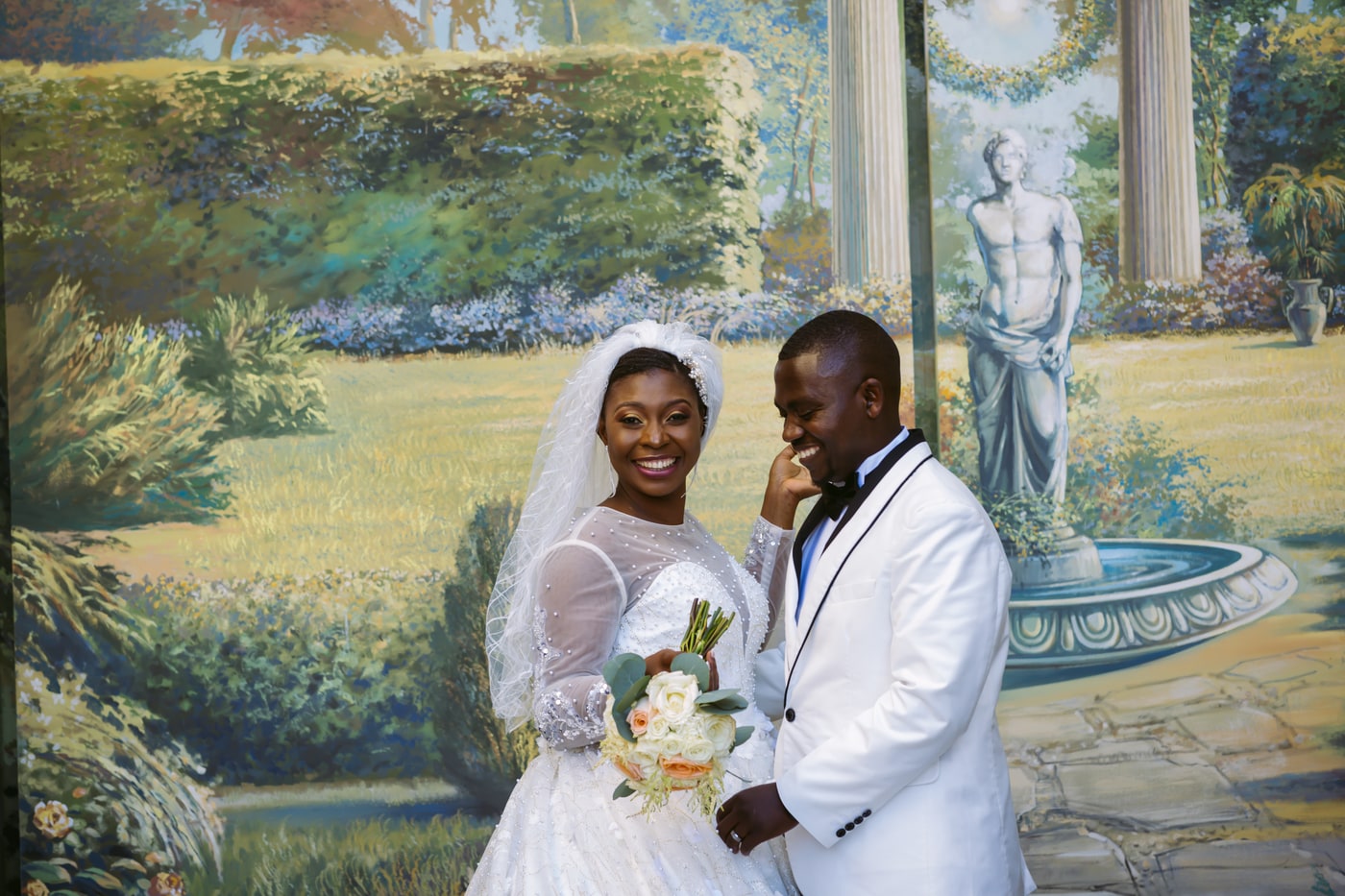 Wedding couple portrait with painted garden backdrop and full-body framing.