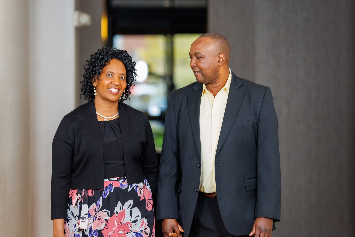 Formal couple walking together in clean venue light.