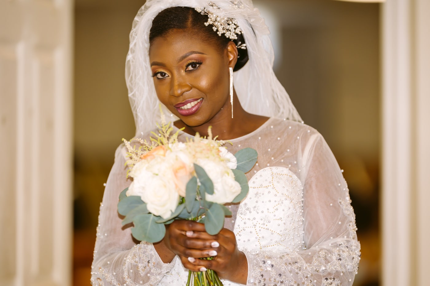 Bridal portrait with direct gaze, veil detail, and bouquet color.
