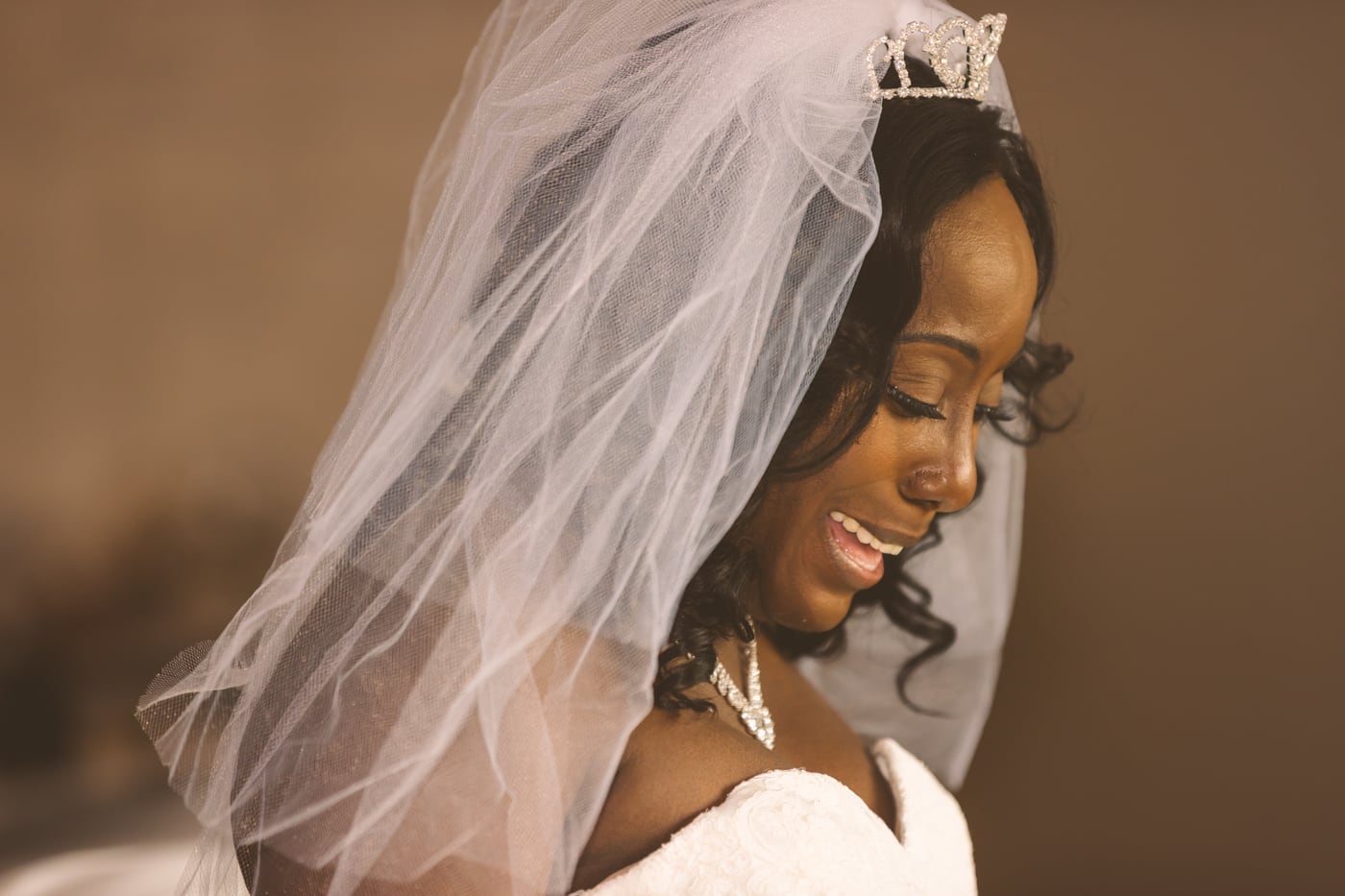 Bride in veil smiling in a quiet wedding portrait.