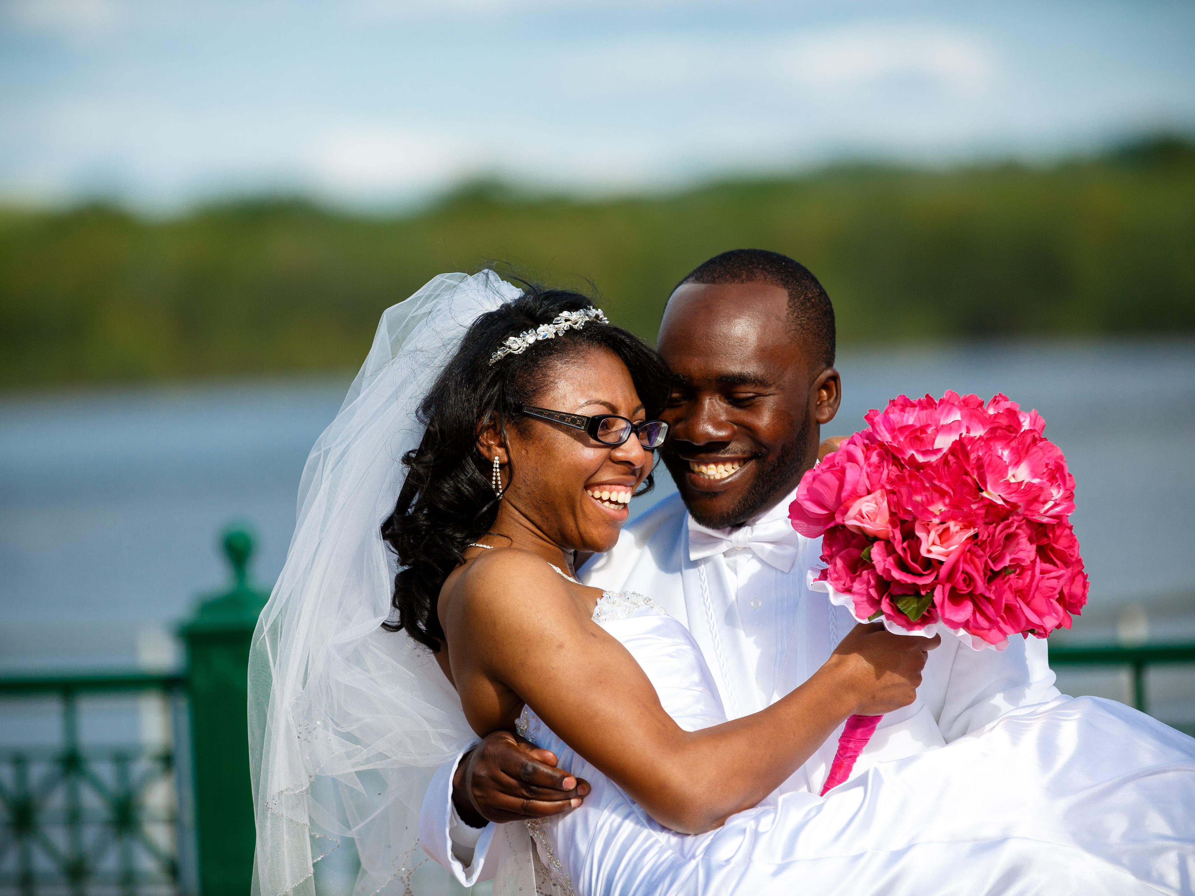 Lakeside wedding couple laughing together with bouquet detail.